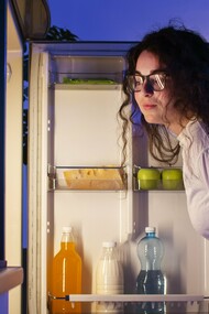 A woman studying her fridge, symbolizing the need to look deeper than dates and cool air