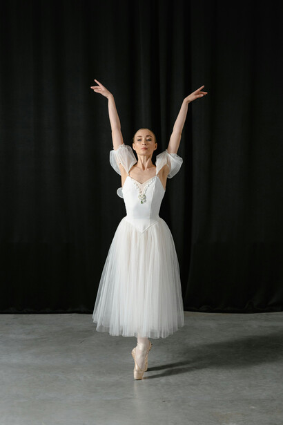 Graceful woman in a white dress performing an elegant ballet dance
