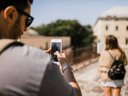 A man taking photograph of woman looking at map standing on street