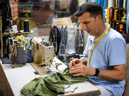Experienced tailor repairing garments in a workshop, practicing visible mending and preserving traditional textile craftsmanship