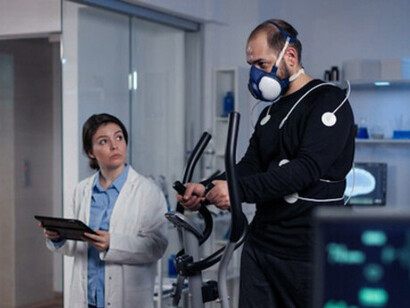 A team of medical researchers assessing a man’s VO2 performance during a run, with a mask on, as an EKG scan displays data on the computer screen in the laboratory