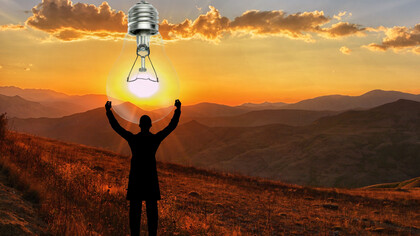 A man holds a lightbulb in the sky, powered by the sun