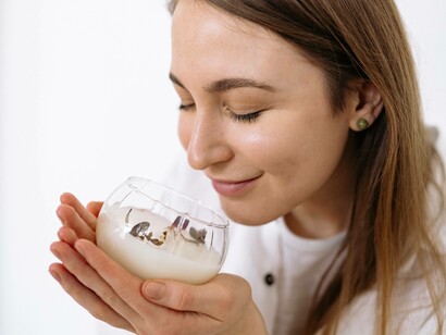A woman smiling as she smells the candle and has a positive vision