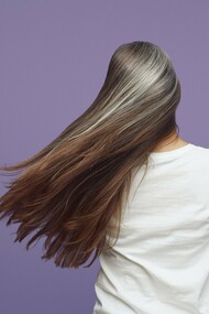 Long brunette hair accented by soft silver strands, reflecting the biological changes that influence hair pigmentation