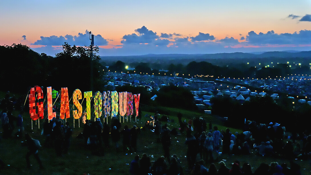 The Glastonbury Festival 2011 captured at night, glowing with lights, music, and the energy of thousands of festivalgoers