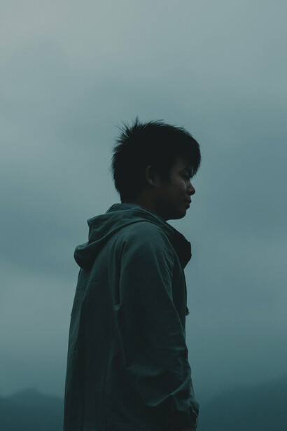 A man in a hoodie standing in a foggy forest, symbolizing a foggy state of mind