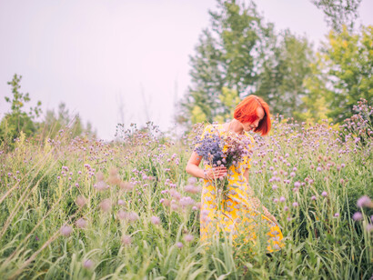 Mujer en vestido recoge flores de una pradera. Ese lugar en el que se puede elegir lo que más conviene, o lo que más le da plenitud o satisfacción a una necesidad del presente