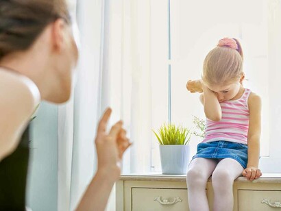A mother wagging her finger at her crying child giving us the impression that she prefers, at this point, to be the authoritarian figure rather than the considerate parent