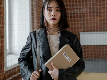 Woman in a black leather jacket holding a brown paper bag, facing bullying at school