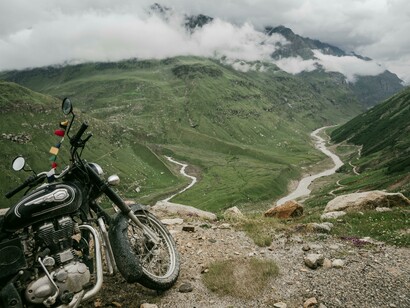 A motorcycle parked in front of lush green Himalayan mountains in Nepal, capturing a sense of adventure and stillness