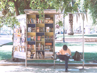 Joven sentado al lado de un kiosko de libros en la ciudad de Santiago de Chile