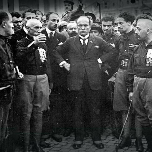 Benito Mussolini al congresso fascista di Napoli, tenutosi come "prova generale" della marcia su Roma attuata pochi giorni dopo. Con lui alcuni dei quadriumviri: da sinistra Emilio De Bono, Italo Balbo e Cesare Maria De Vecchi, 24 ottobre 1922