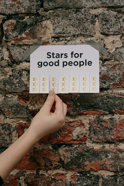 A hand tears a piece of paper from the wall of stars, a reward system for good people