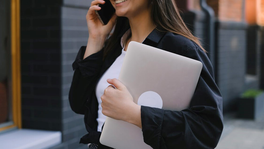 A woman holding a laptop, representing gender equality in business, corporate board diversity, and women in leadership, all contributing to gender balance in the workplace
