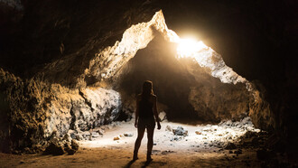 Mujer observa un halo de luz en el interior de una caverna en el desierto de Mojave, Estados Unidos