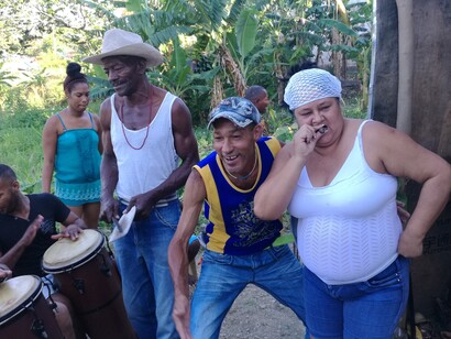 La gente baila y canta durante una ceremonia de santería. Un asistente de santero fuma un cigarro. Mantilla, La Habana, Cuba