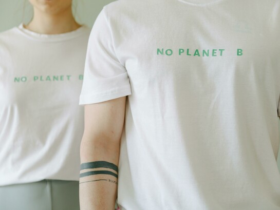 People wearing white-themed shirts with slogans such as ‘No Planet B,’ representing sustainable fashion and eco-friendly clothing for the future