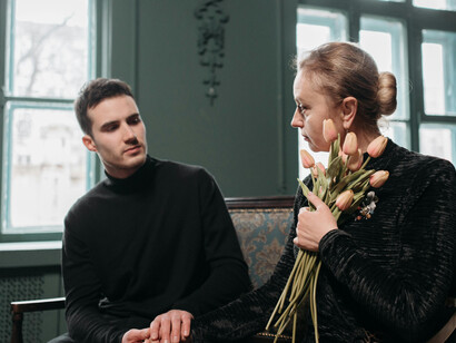 A grieving mother and her son mourn together during a solemn funeral service