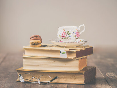 Una pequeña pila de libros con una taza y galletas encima