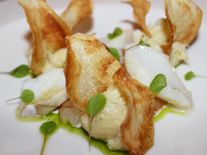 Baccalà cotto a vapore, sfaldato, marinato in olio su gambero rosso crudo e chips di patate. Foto di Sara Biondi