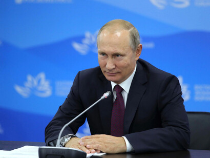 Vladimir Putin sitting down at a press conference