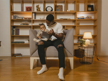 A father reading a story to his baby, depicting the significance of passing down the stories from generation to generation and preserving cultural traditions