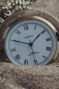 A pocket watch sunk in the sand