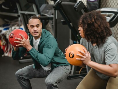 A duo helping each other maintain their fitness with a medicine ball