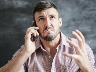 While on the phone with customer support, a man looks frustrated as the conversation drags on, with no clear solution in sight