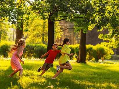 Two little girls and boys playing red ball on green grass in the park in summer day