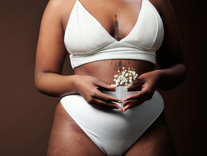 A woman gently holding a menstrual cup adorned with delicate berries, representing the reclaiming of menstruation as a natural and dignified experience