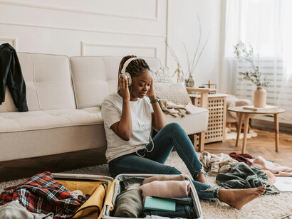 A woman listens to music through her headphones while packing