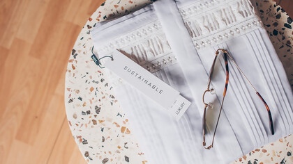 Sustainable fashion, sunglasses sitting on folded white shirt, on top of terrazzo side table