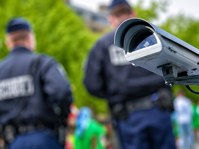 Police officers stand beside a security CCTV surveillance system with a blurred urban background