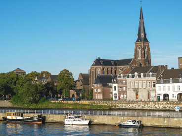 Maastricht, the Netherlands, historic riverside architecture and church towers reflecting the timeless charm of Maastricht under a clear summer sky