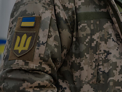 A Ukrainian military serviceman proudly wears the flag and coat of arms trident on his uniform, symbolizing his allegiance to the Armed Forces of Ukraine