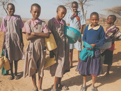Six children standing on desert in a remote region of northern Kenya, water is a few kilometres away in a dried up river bed and these girls walk there and back a few times a day