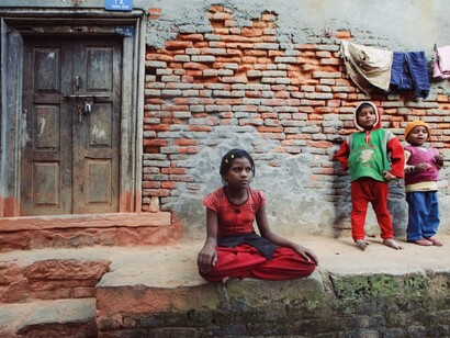 A group of children outside a deteriorating house, reflecting the urgent need to direct wealth toward improving everyday lives