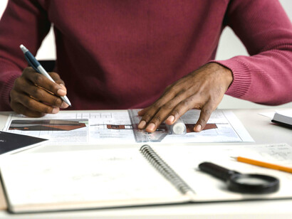 Drawing blueprints, an architecture student brings design concepts to life through focused study and sketching