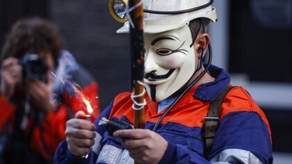 Un minero enmascarado enciende un petardo durante una protesta en Asturias