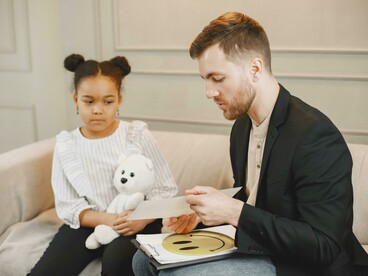 A family attends a therapy session with their young child, discussing emotional trauma and healing together