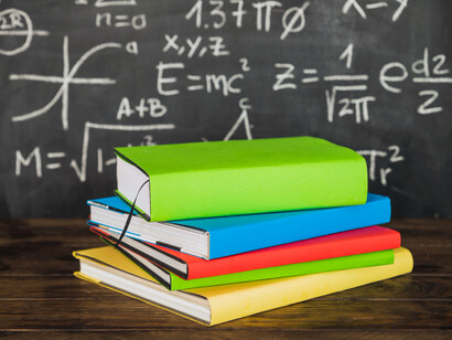 Libros apilados sobre una mesa y un pizarrón con cuentas en representación de la educación tradicional. La educación debe adaptarse a los cambios tecnológicos