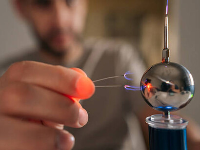 A person demonstrating a Tesla coil generating electrical arcs and plasma during a high-voltage physics experiment