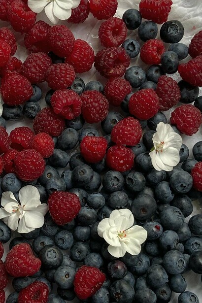 A mix of blueberries and strawberries with flowers