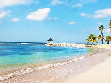 Jamaican beach with palm trees. A tranquil daytime scene of a white sand shoreline in Jamaica, lined with palms and set against a deep blue sky