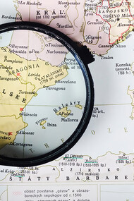 A magnifying glass revealing a map of Spanish cities