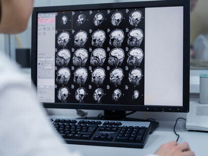 A radiologist examining a patient's brain MRI scan results on a computer monitor in the control room