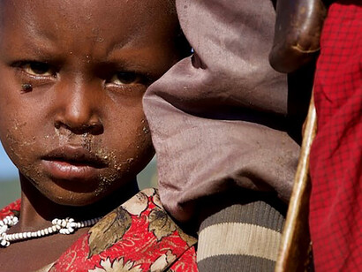 An infant finds solace in holding his mother's hand, Maasai, Tanzania