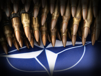 Military bullets stacked up high on the NATO flag