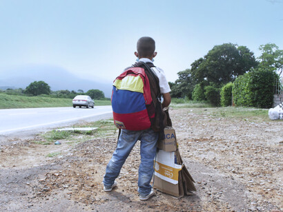 Niño inmigrante junto a una autopista en Perú